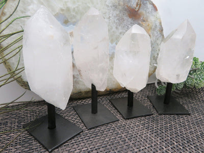 multiple crystal quartz points on metal stand displayed to show the differences in the shapes