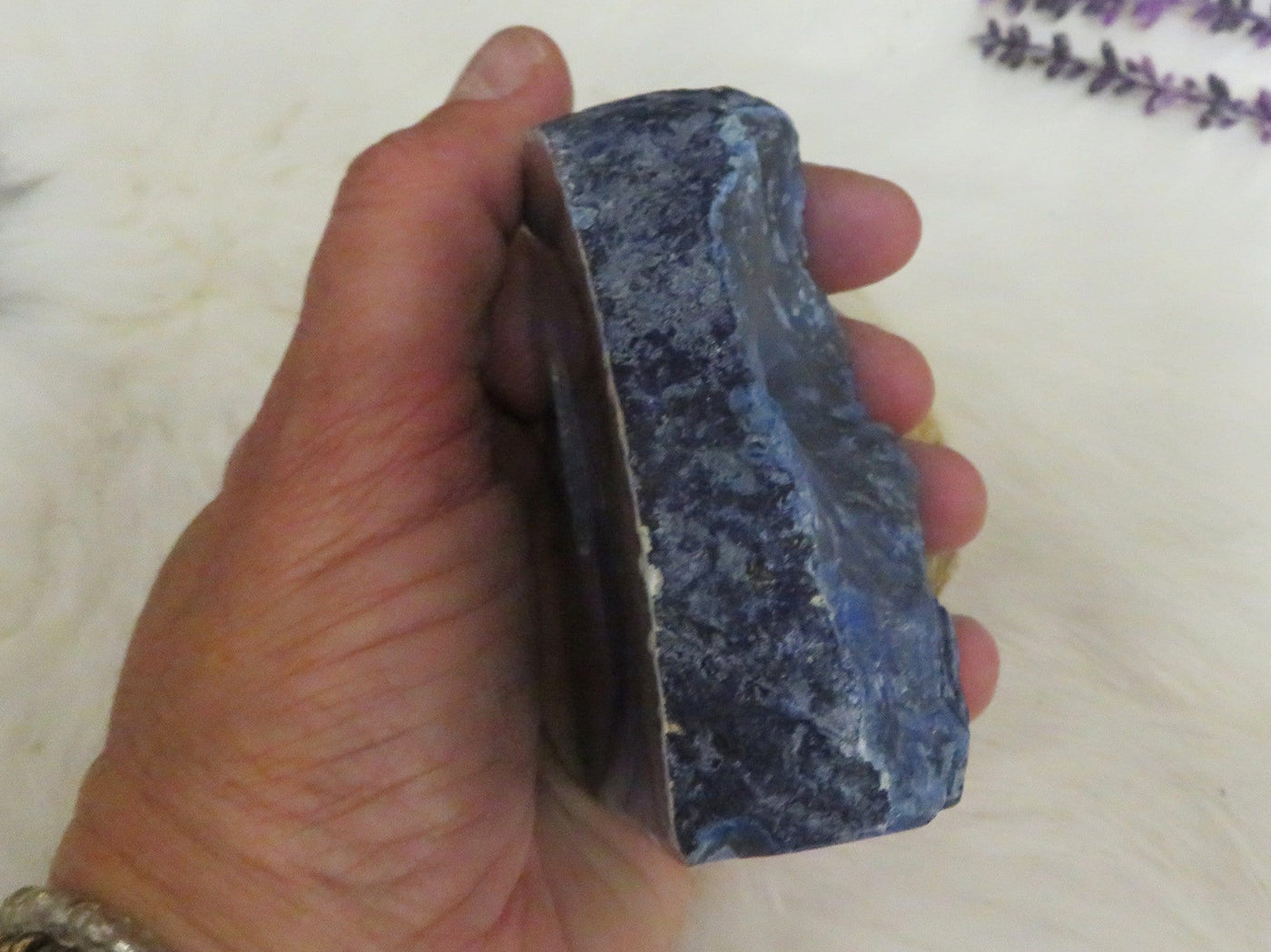 hand holding up blue agate cut base to show the side of it