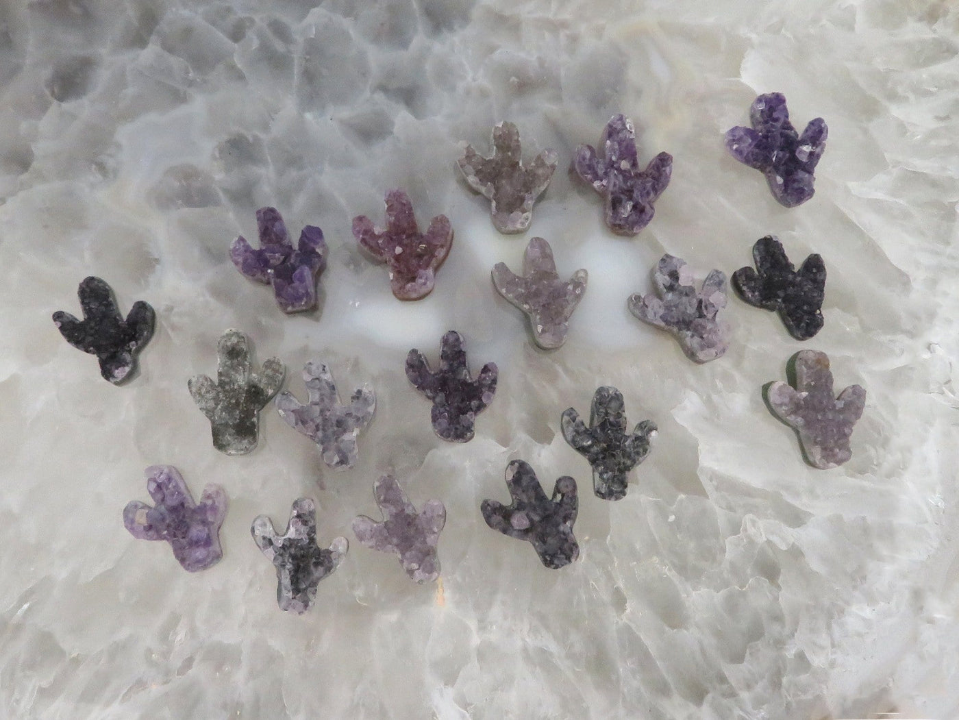 Multiple amethyst cactus being are being displayed on a crystal quartz platter. 