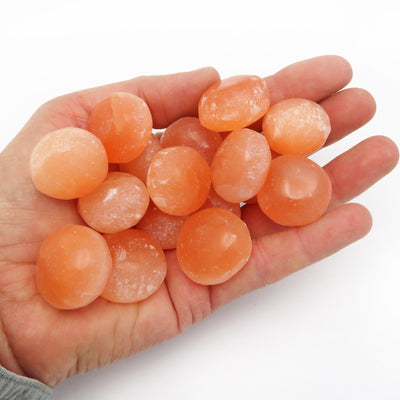 Orange selenite spheres assorted in a hand.