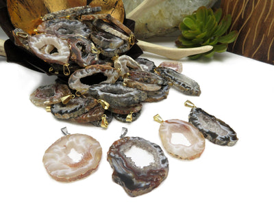 Multiple agate geode natural pendants shown with silver and gold bails. Many pendants in the background within an alter.