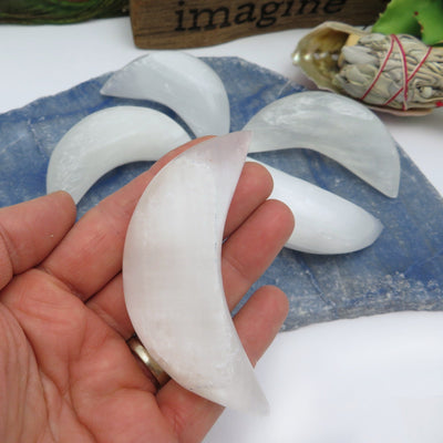 selenite crescent moon in hand for size reference with others in background