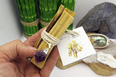 Close up view Hand holding Palo Santo Bundle with Amethyst pendant