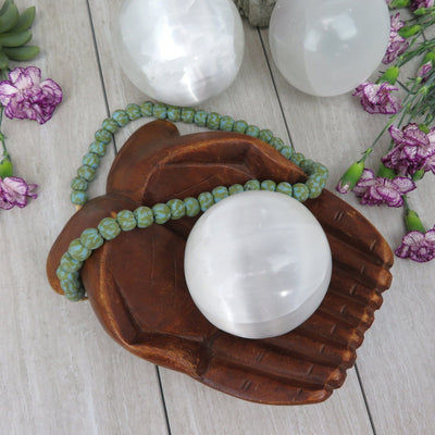 overhead view of selenite sphere in wooden hand bowl with others in background display