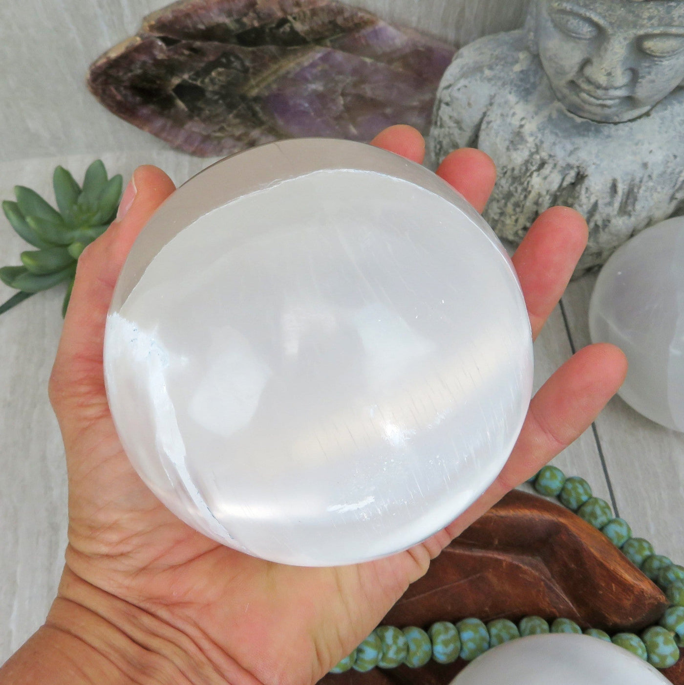 selenite sphere in hand for size reference