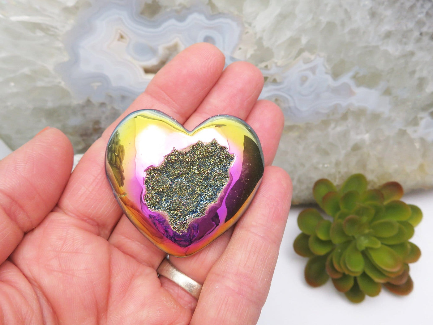 Titanium Druzy Hearts in rainbow in a hand for size reference