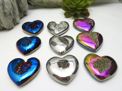 Titanium Druzy Hearts in mystic blue, platinum and rainbow laid out  on a table shot from an angle to show thickness