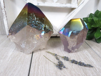 2 Rainbow Titanium Coated Crystal Points on wooden table with decorations in the background
