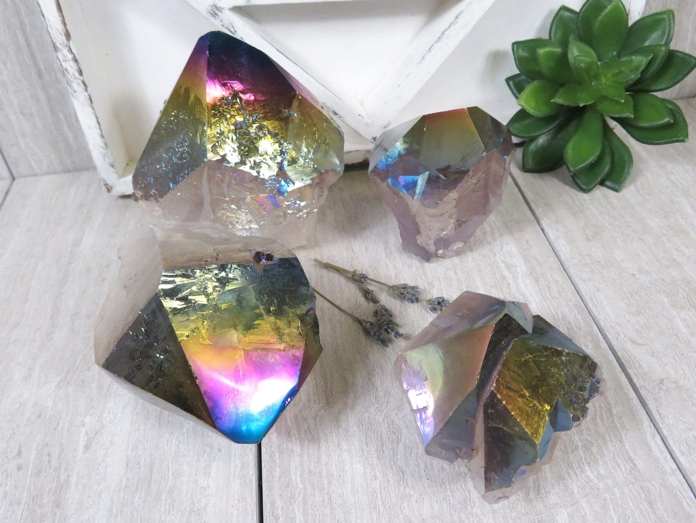 4 Rainbow Titanium Coated Crystal Points on wooden table with decorations in the background