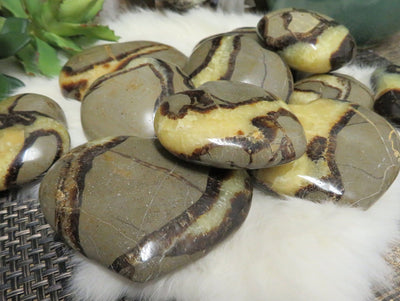 many septarian polished heart stones in a pile on display