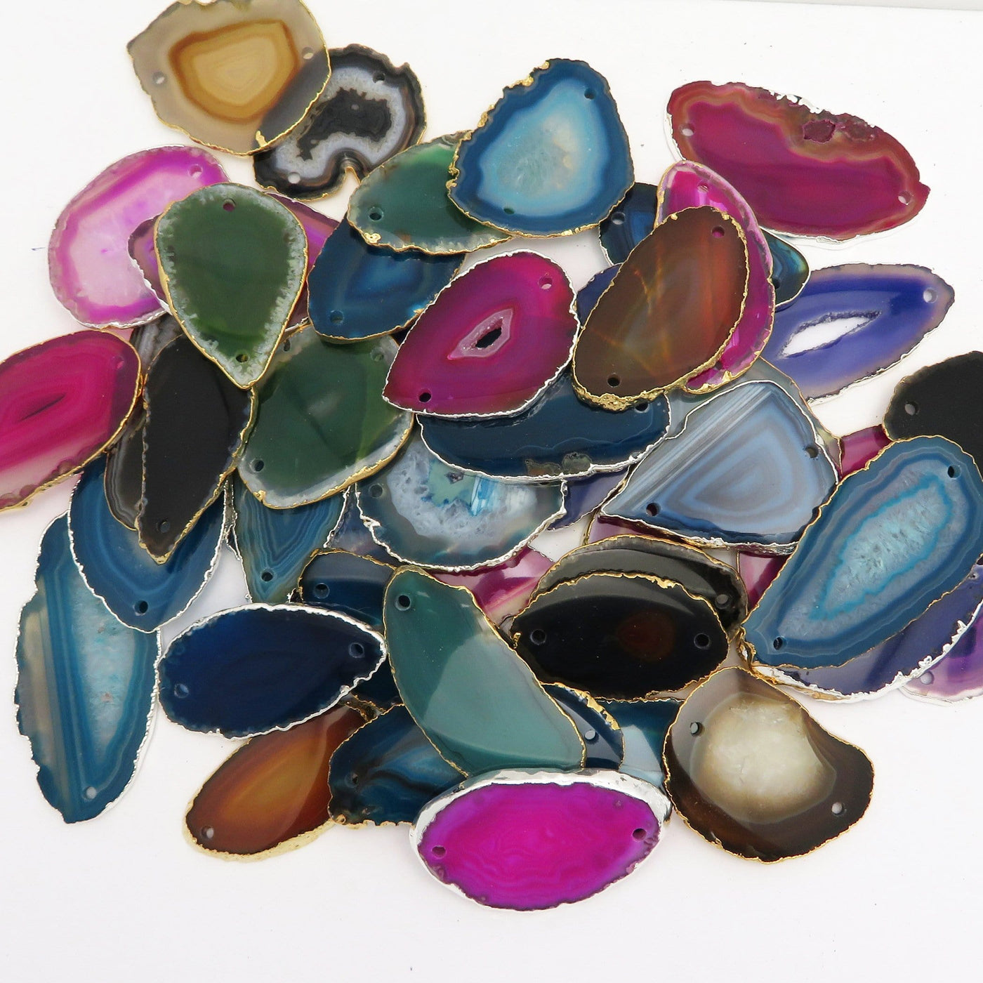Picture of all the variety of colors we have available for our agate slice plated edge double drilled pendants, displayed on a white background.