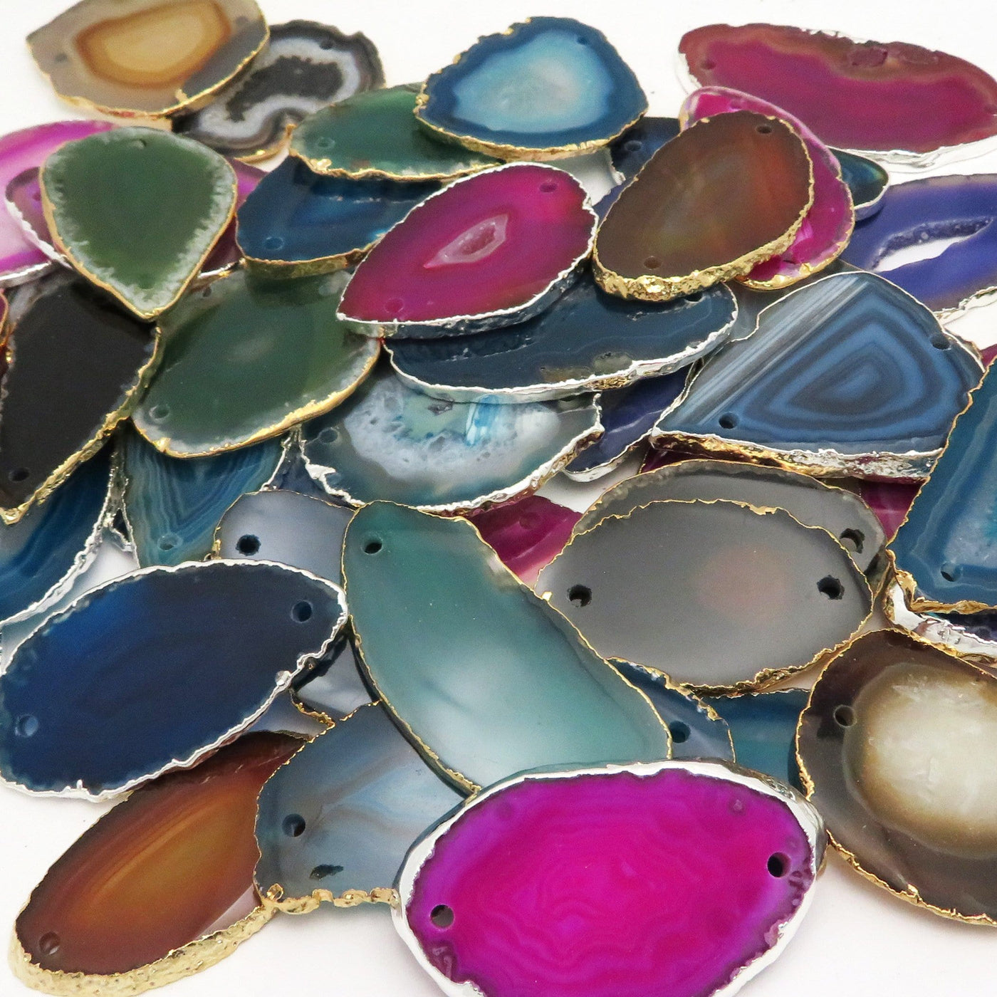 Picture of all the variety of colors we have available for our agate slice plated edge double drilled pendants, displayed on a white background.
