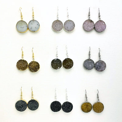 9 assorted round druzy earrings with silver and gold earwires.  Druzy colors range and are white, white with black spots, light purple, various shades of brown and tan, various shades of gray and orange brown.  Two of the earrings on the last row are titanium treated and sparkly black.