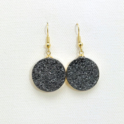 Close up of round black titanium treated druzy earrings with gold plating.