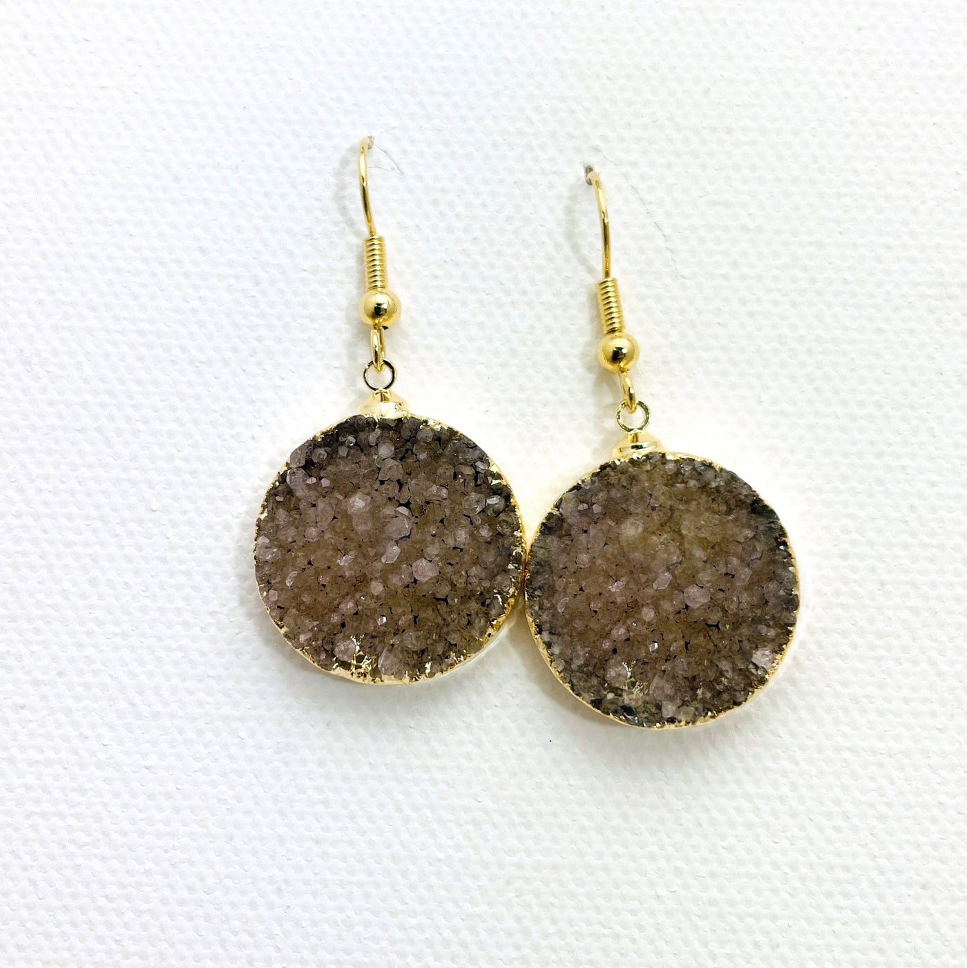 Close up of a pair of brown druzy earrings with gold plating.