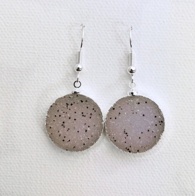 Close up of white druzy earrings with black spots that are silver plated.