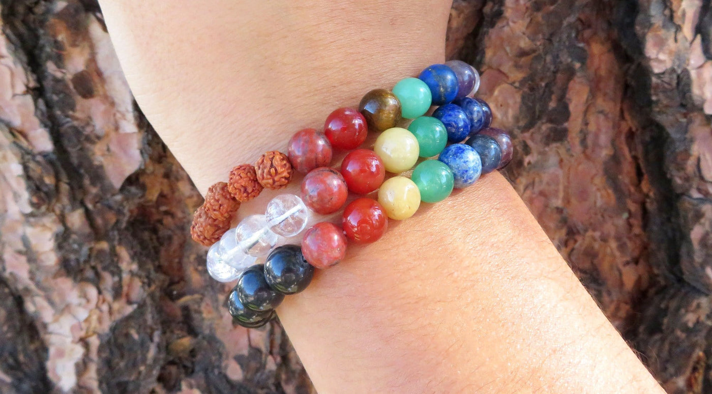 varied healing stone bracelets being warn to show size on a white background