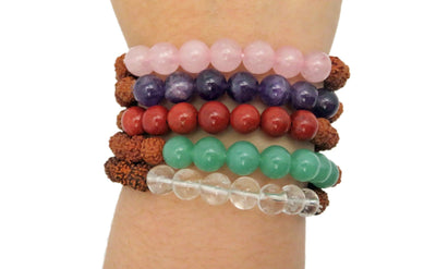varied healing stone bracelets being warn to show size on a white background