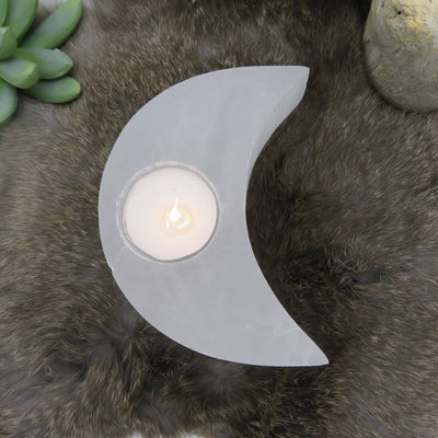 close up of selenite crescent moon candle holder with candle (not included with purchase) for details