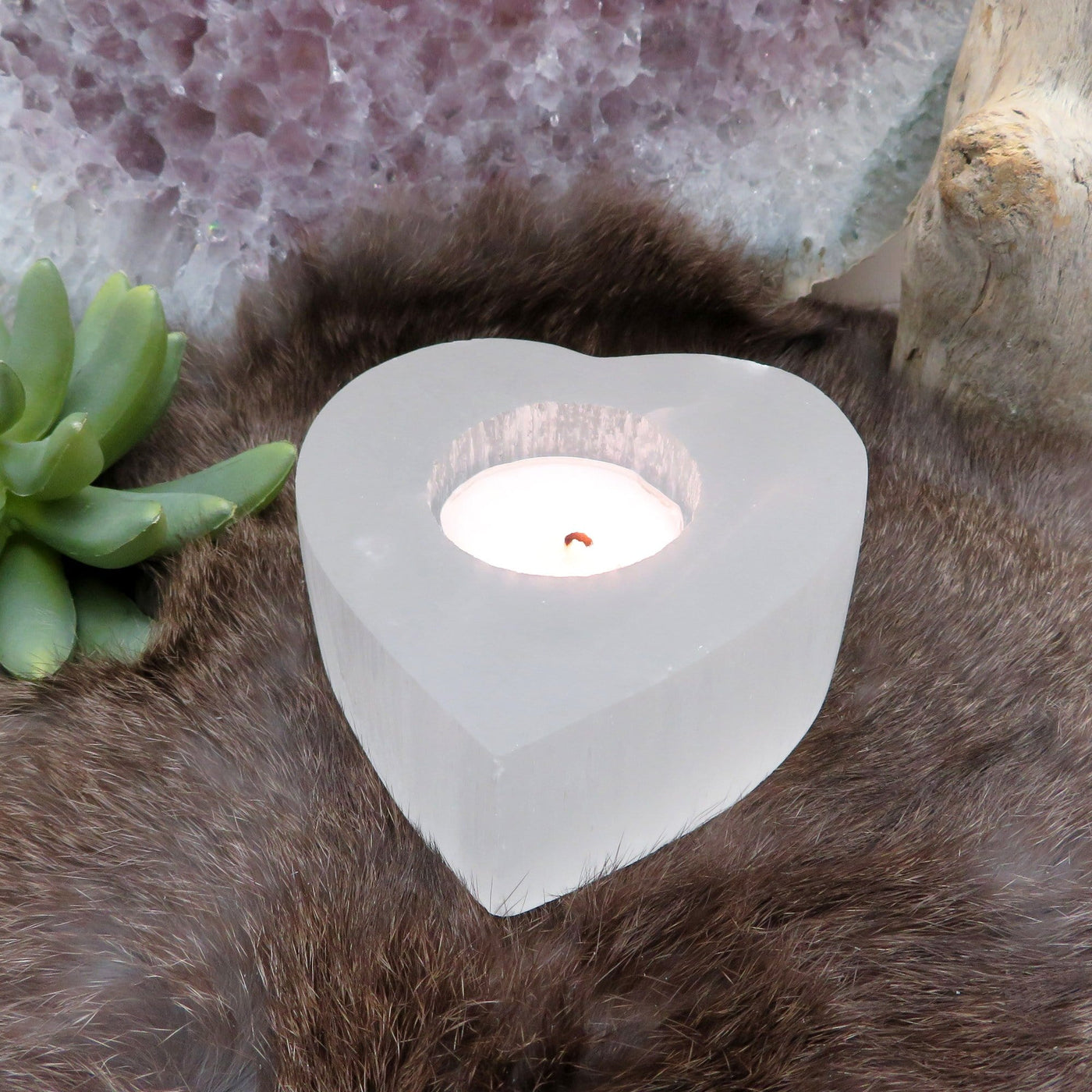 selenite heart shaped candle holder on display with candle (not included with purchase)