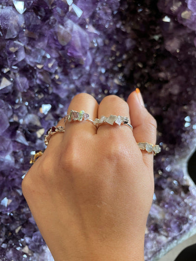 Fist wearing Raw Stone Rings on amethyst background