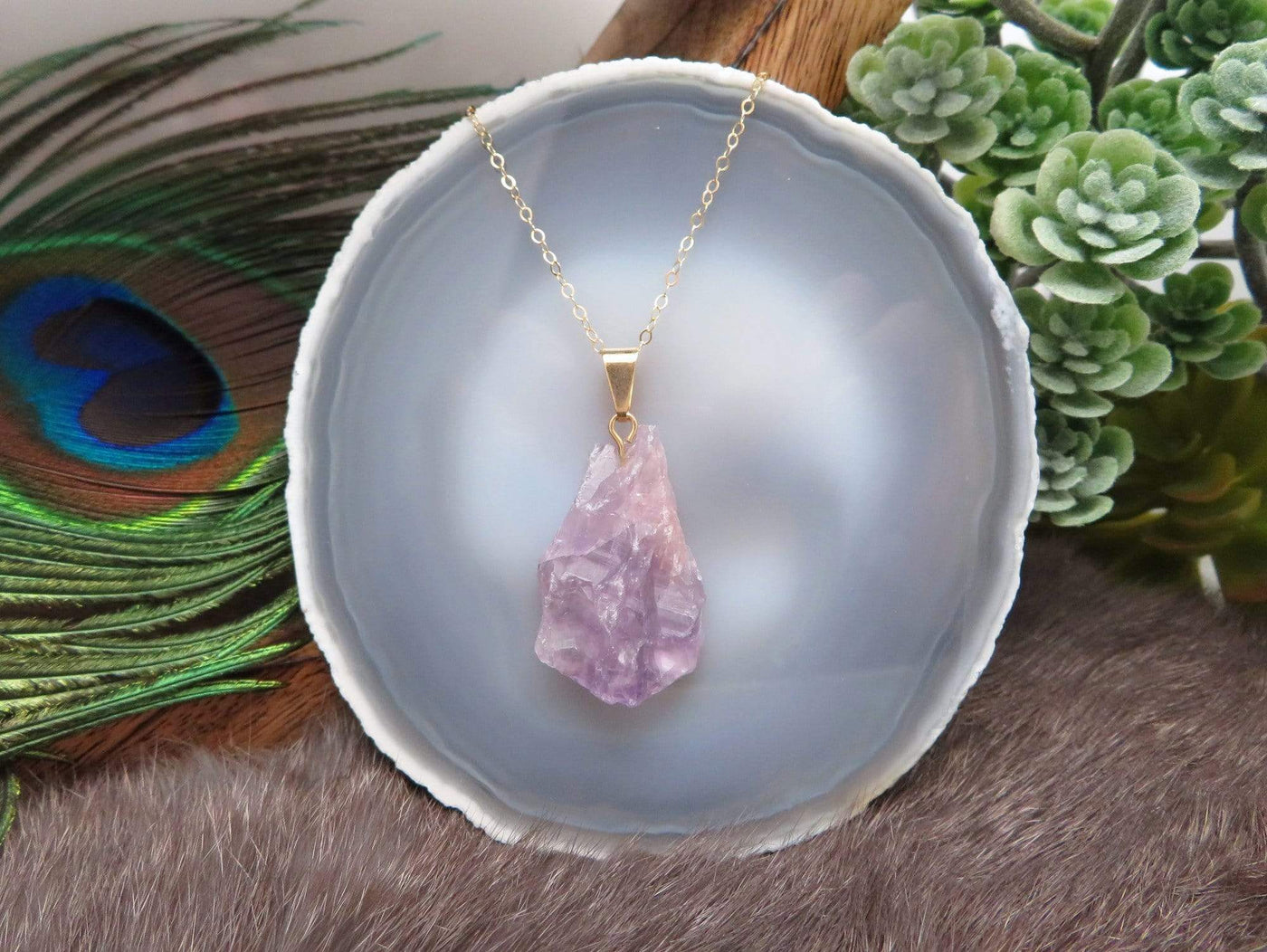 Amethyst rough stone pendant on a gold chain hung from an agate slice.