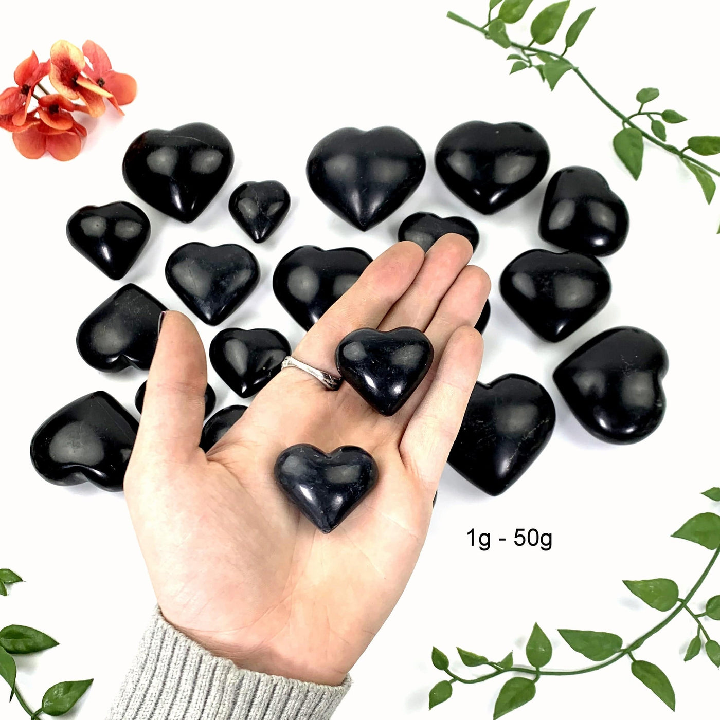 2 - 1gram to 50 gram black onyx polished hearts in a hand over the opening photo