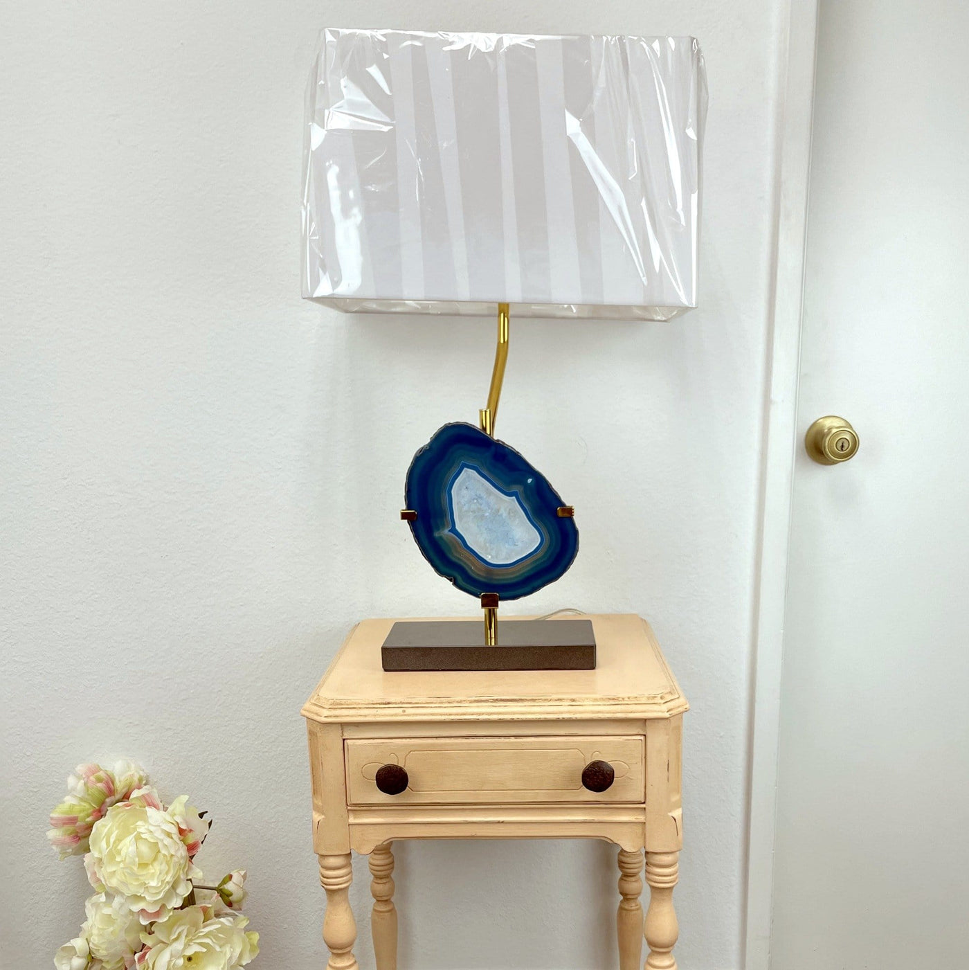 A teal agate slice on a wood base gold metal lamp on top of a table