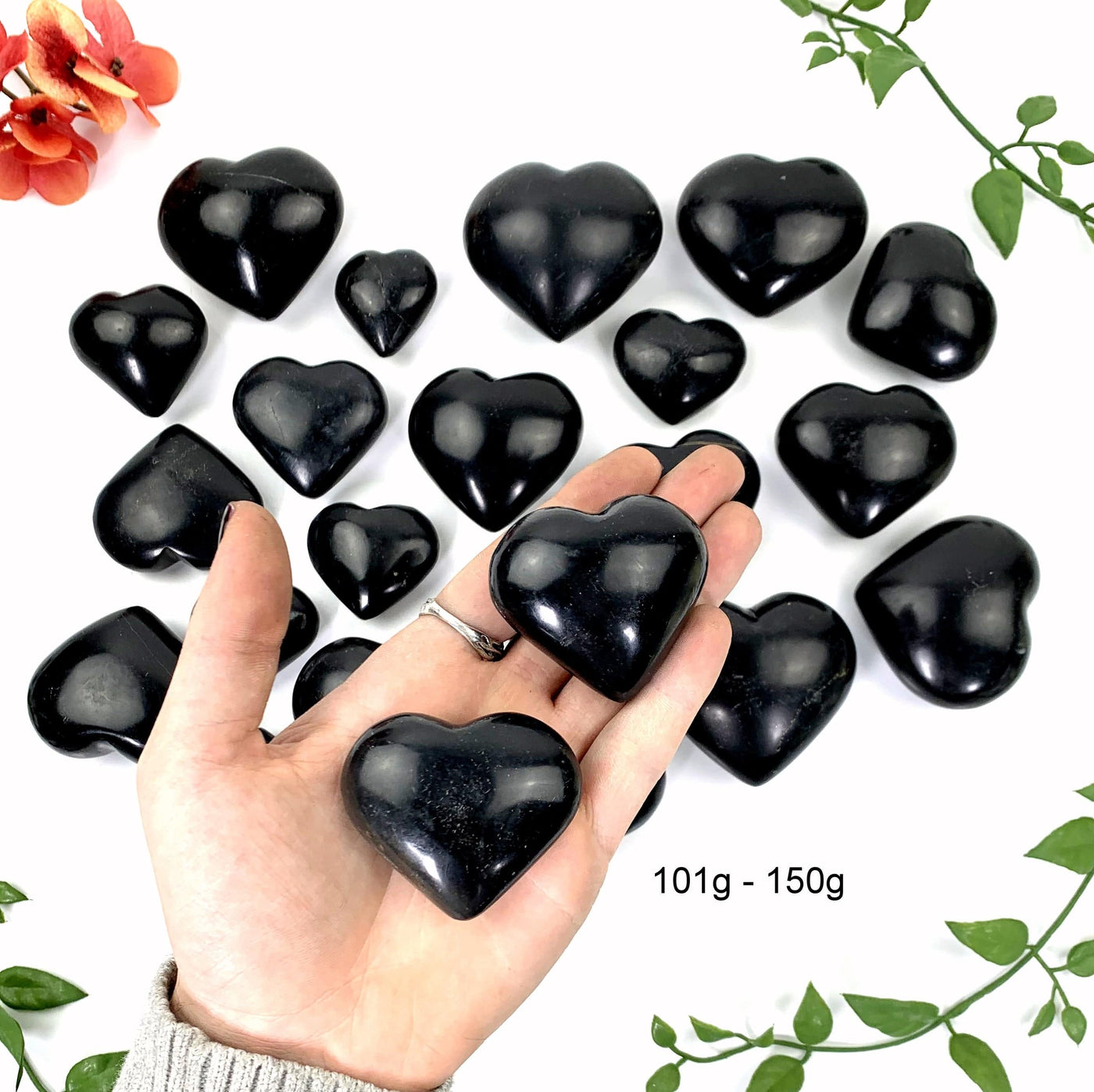 2 - 101gram to 150gram black onyx polished hearts on a hand in front of the opening shot