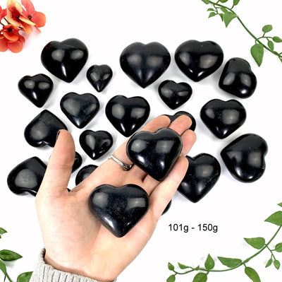 2 - 101gram to 150gram black onyx polished hearts on a hand in front of the opening shot