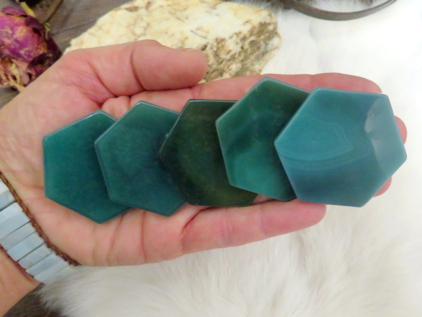 green agate hexagon slices displayed in hand for color variations and size reference