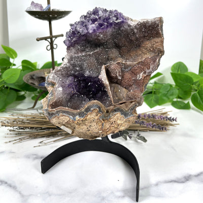 Amethyst Formation on Metal Stand with decorations in the background