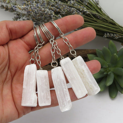 many selenite silver toned key chains in hand for size reference