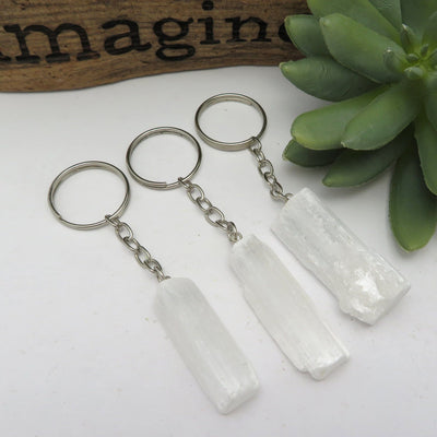 three selenite silver toned key chains laying flat for possible variations