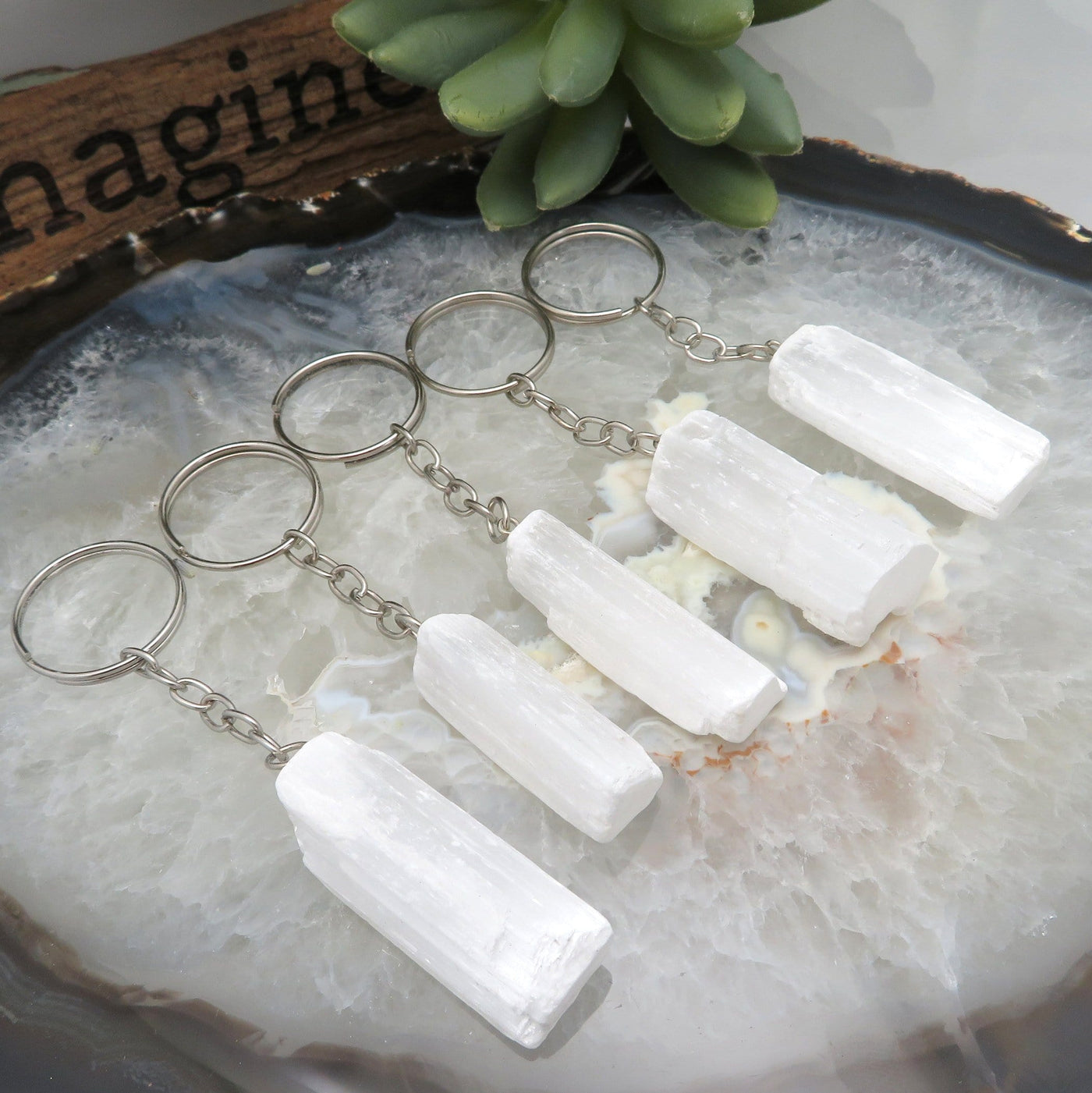 angled view of selenite silver toned key chains on display for possible variations