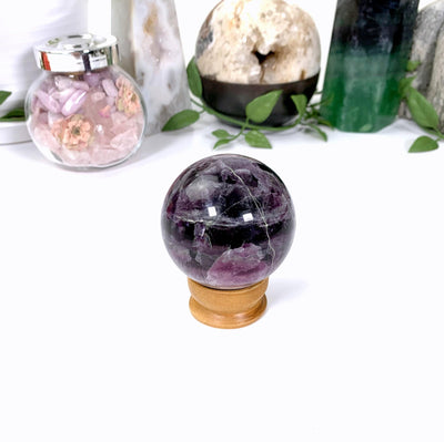 Purple fluorite sphere on a wooden stand on a white background