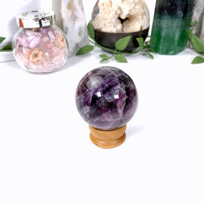purple fluorite sphere on a white background on a wood stand