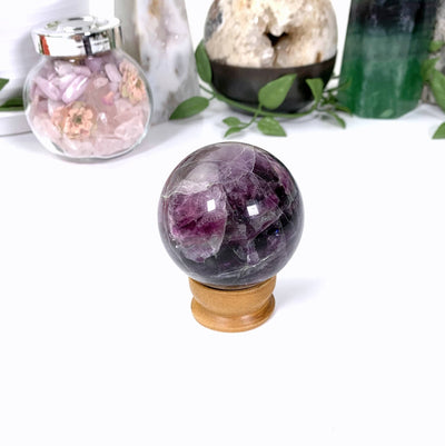 back view of purple fluorite sphere on a stand on white background