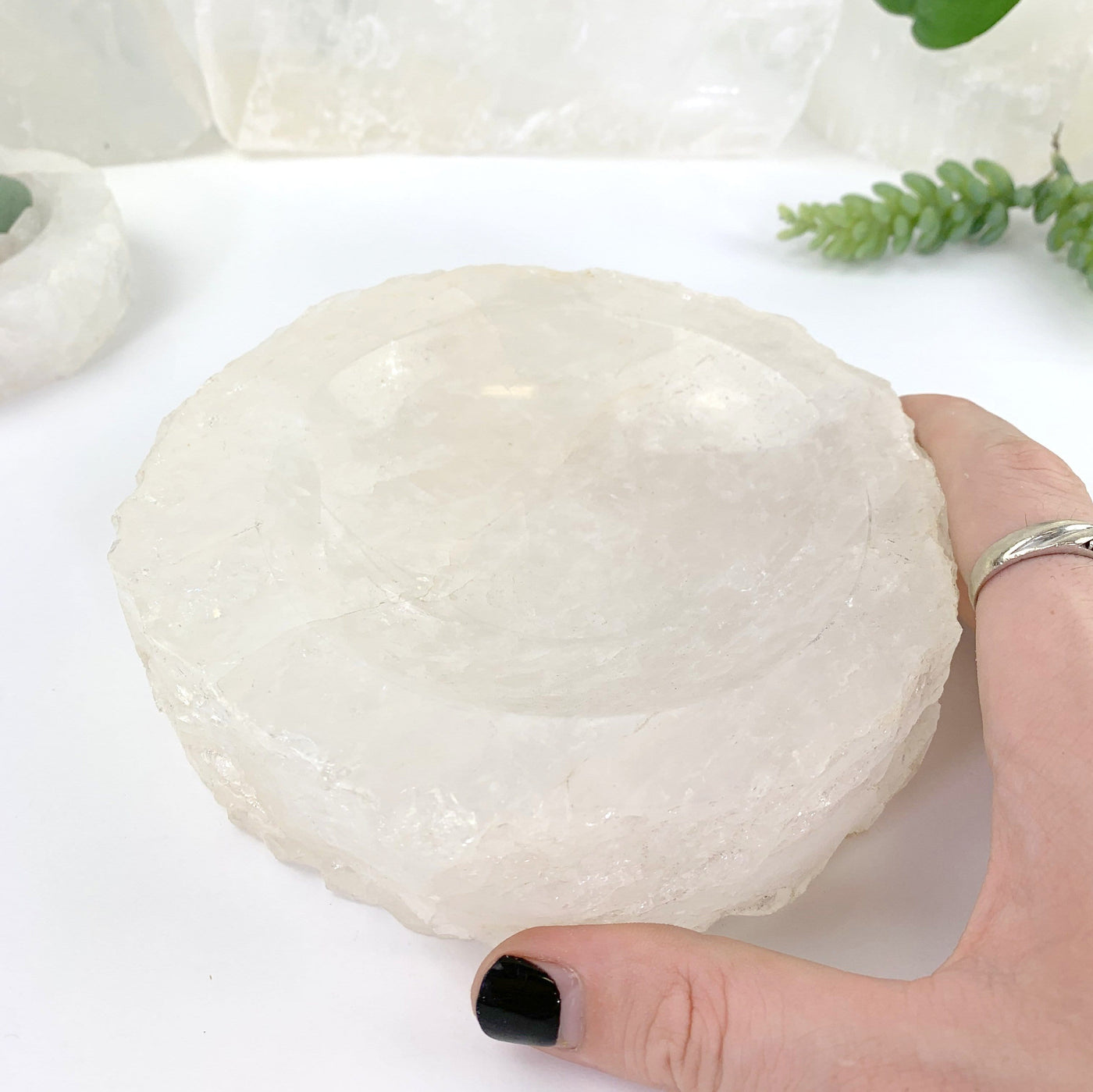 hand holding Crystal Quartz Display Bowl with decorations in the background