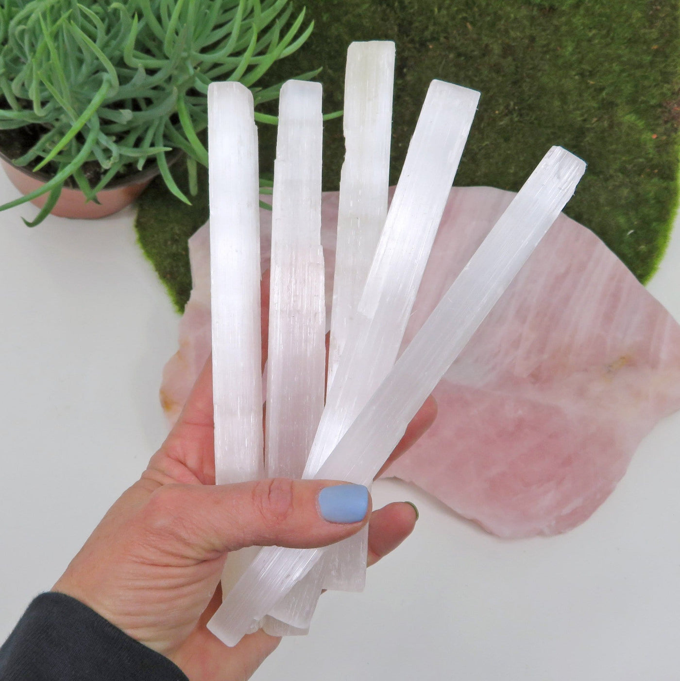 many selenite rods in hand for size reference and possible variations 