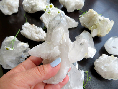 hand holding up crystal quartz cluster with others in the background