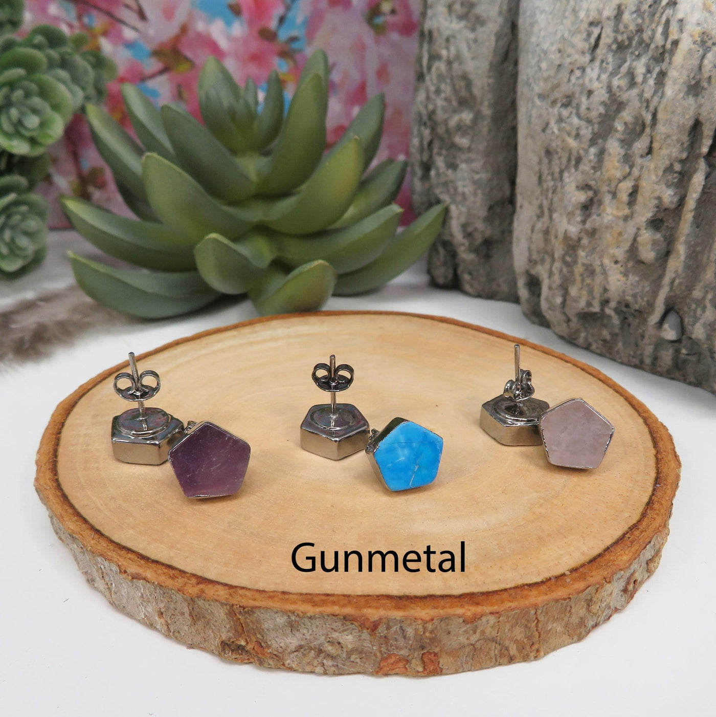 gunmetal pentagon stud earrings on a table