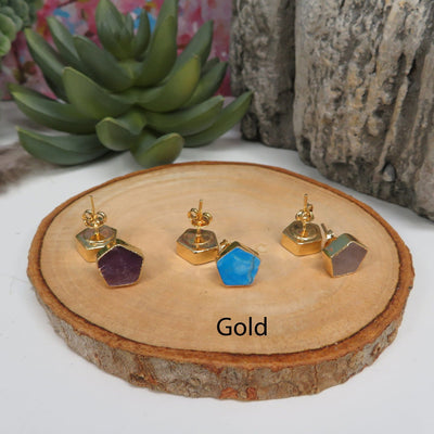 gold pentagon stud earrings on a table