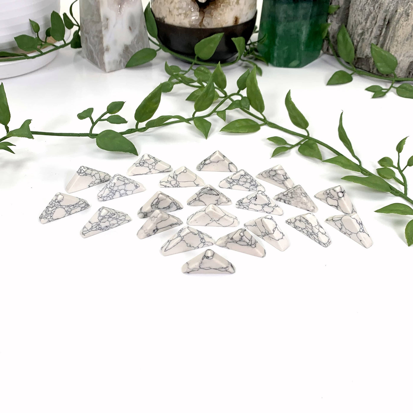 white howlite triangles standing up on a white background surrounded by vines