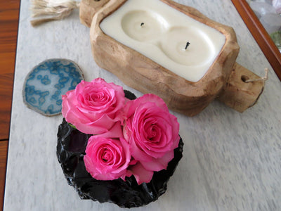 Rough Stone Planter with roses inside next to wood candle holder
