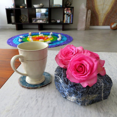 one sodalite planter with three roses inside on a table with a teacup in a home setting