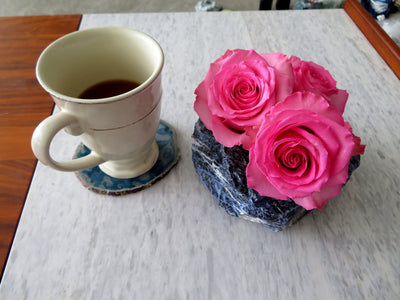 Rough Stone Planter with roses  inside next to a cup of tea