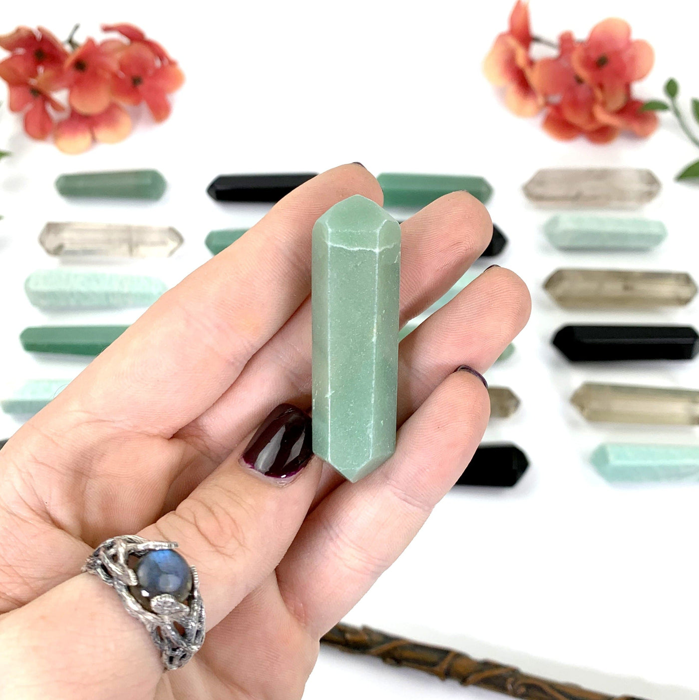 Close Up of Green Aventurine Crystal in Fingers With a White Background.