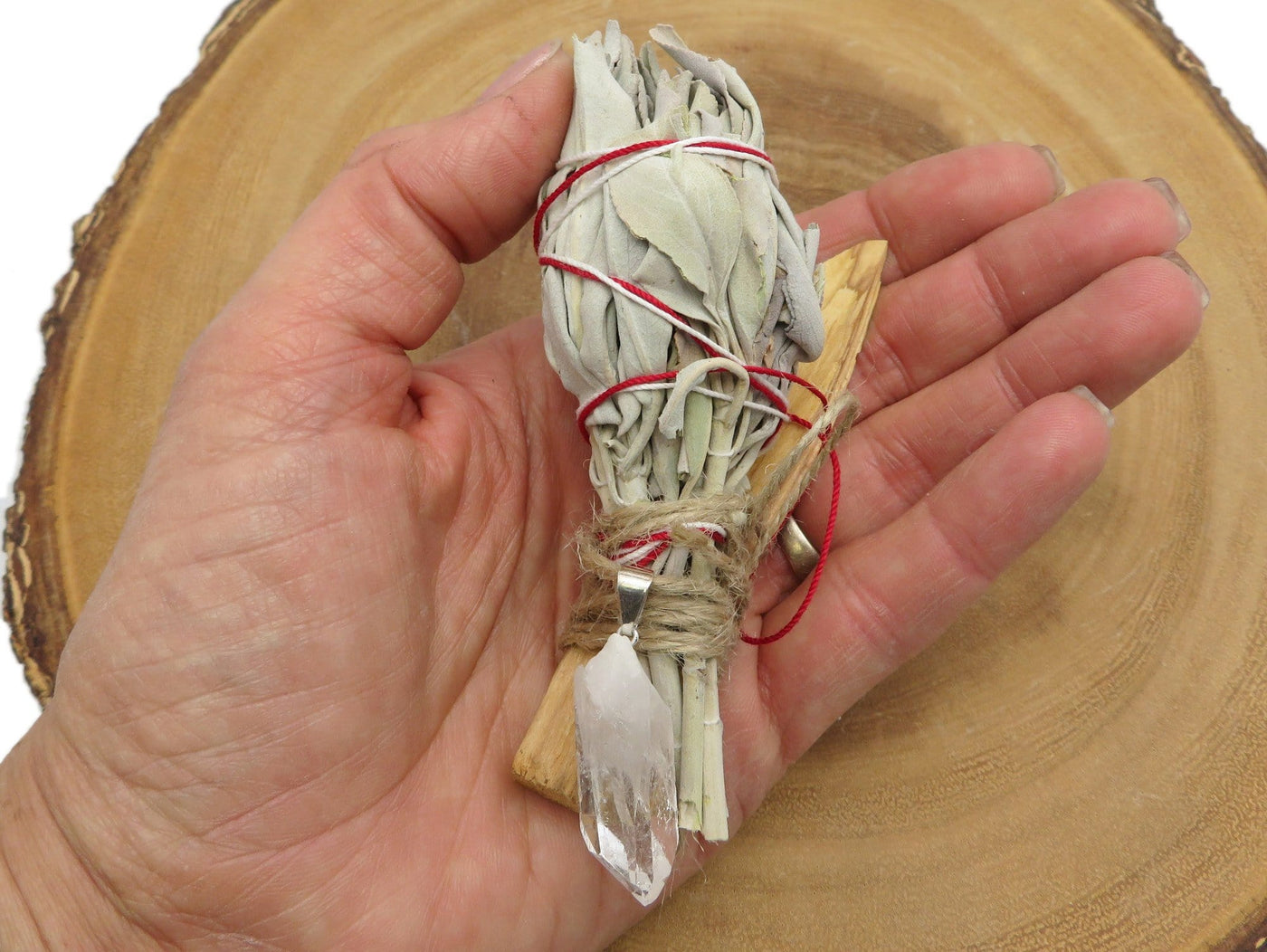 close up of sage palo santo bundle with crystal quartz pendant for size reference and possible variations