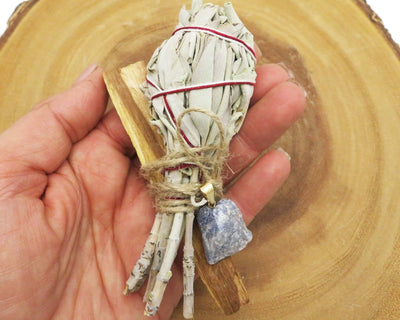 close up of sage palo santo bundle with sodalite pendant for size reference and possible variations